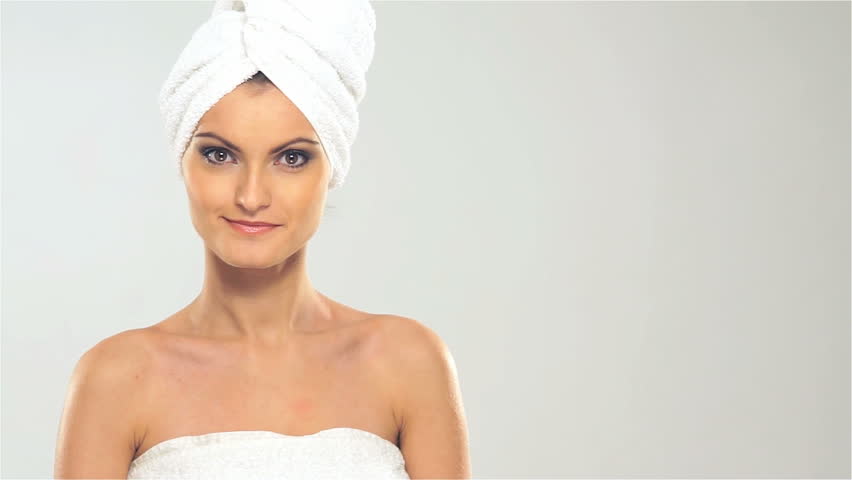 Portrait of young beautiful woman with the towel on her head in spa over grey background