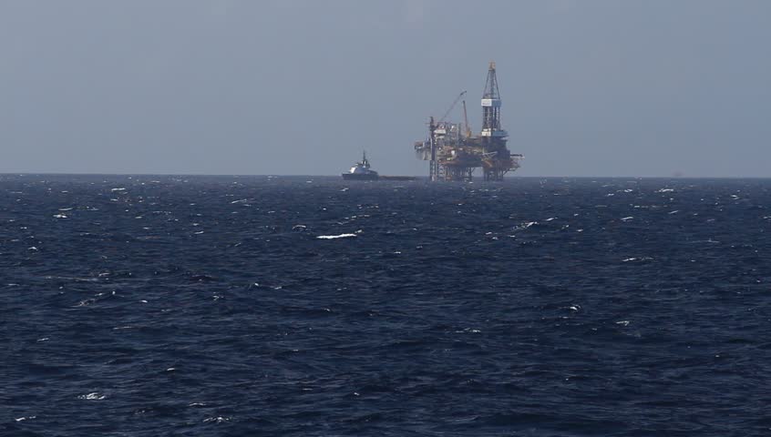 Offshore Jack up drilling rig and crew boat in the middle of the ocean on windy day
