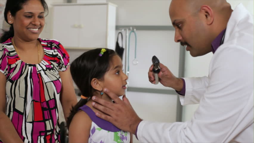 An Indian pediatrician or family doctor listens to the heart of a little girl who is being accompanied by her mother.