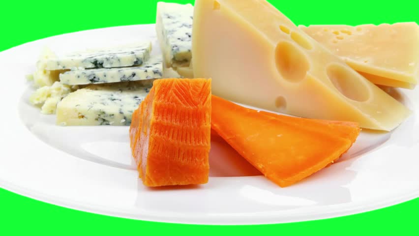 slow motion french delicatessen aged cheeses chops served on white plate with slices on green screen hidef