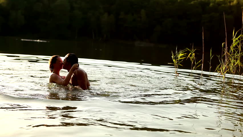 Young couple embracing and kissing in romantic attitude into the water in lonely romantic lake