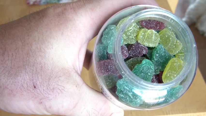 Kids getting vitamins inside large bottle with parent unscrewing cap to allow children to reach in for one.