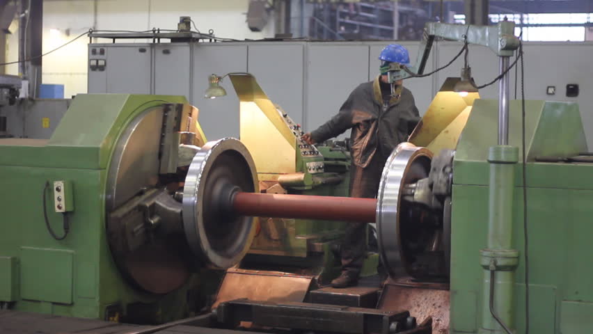 Worker on a machine, metal working lathe a in factory. Machining process in the factory for repair of trains and wagons