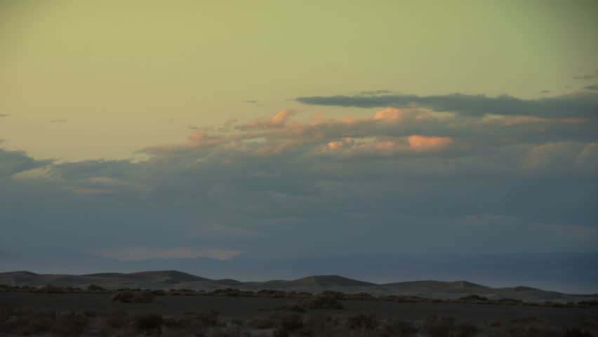 HD - Time lapse sunsetting clouds travel over sand dunes in Death Valley National Park, California, USA.