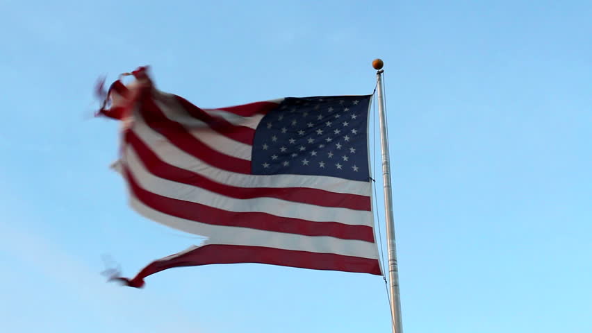 A torn and tattered American flag waves in the wind