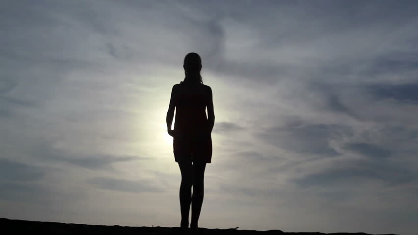 Silhouette of beautiful female sensual dancing over sun