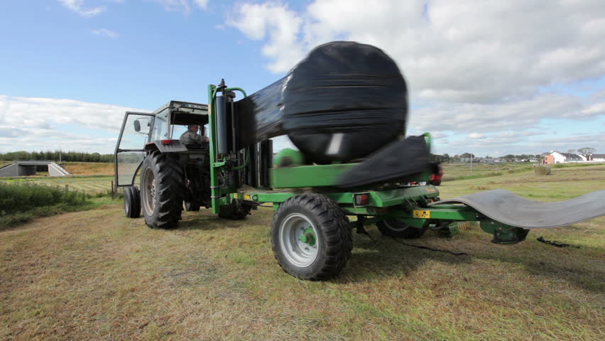 ATHENRY, IRELAND - JULY 26: Tractor wrapping bail of hay with plastic at the field on July 26, 2011 in Athenry, Ireland