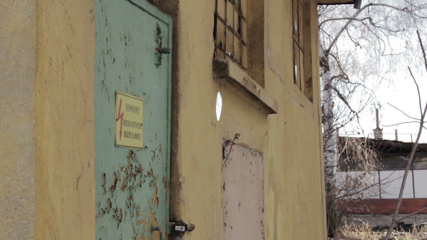 Crane shot of a high voltage sign on a rusty door.
