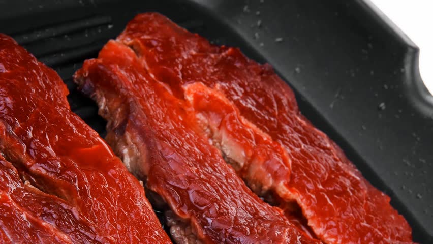 fresh raw bloody beef steaks on black grill plate hidef slow motion intro