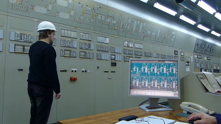 Industrial workers in a control room, working with computers and controls the operation of devices in a petrochemical plant