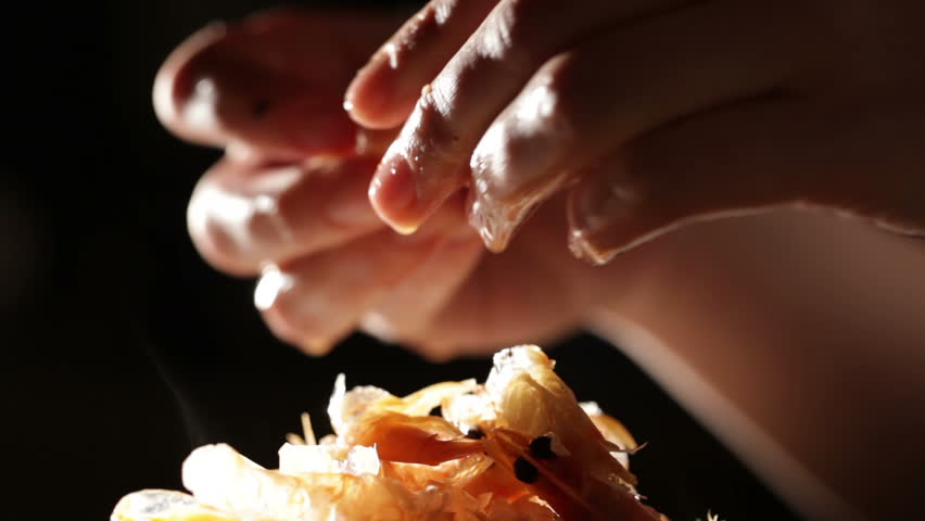 Women's hands are cleaning shrimp. Macro shot backlit.