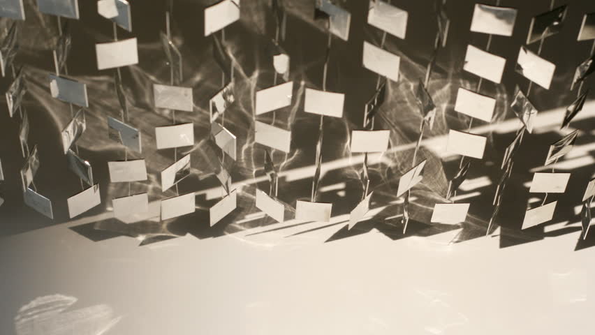 cool metal shapes hanging on wall and moving,with reflection from sunlight
