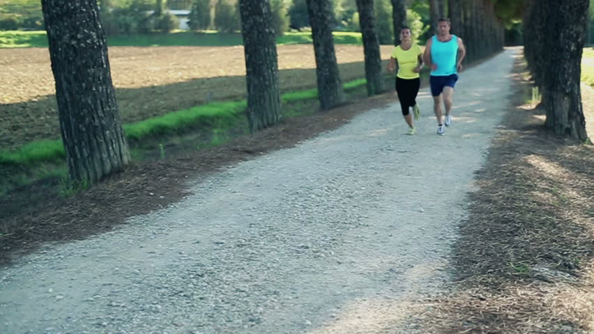 Young couple jogging in summer park, slow motion, crane shot
