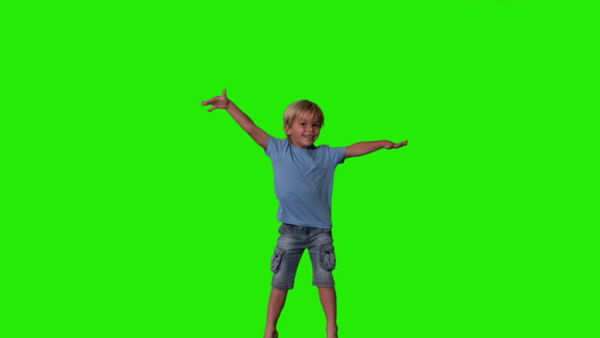 Boy in denim shorts jumping on green screen in slow motion