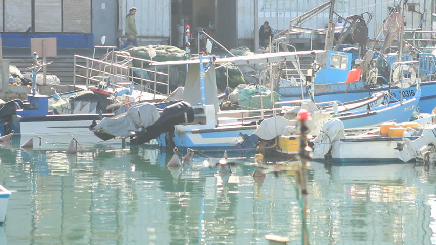 boats being anchored at Jaffa port while people walk behind it