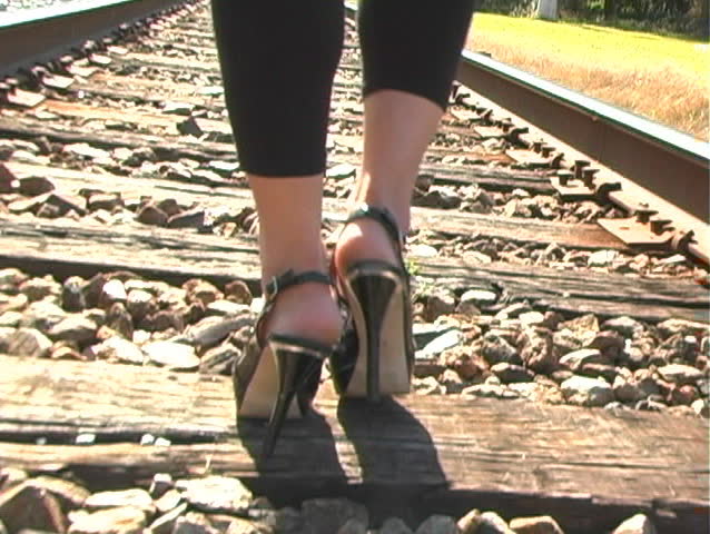 A native-American beauty walks away from the camera on a long stretch of railroad track.  This clip can be used alone or extended frame-accurately with clip b.  Camera cranes up.