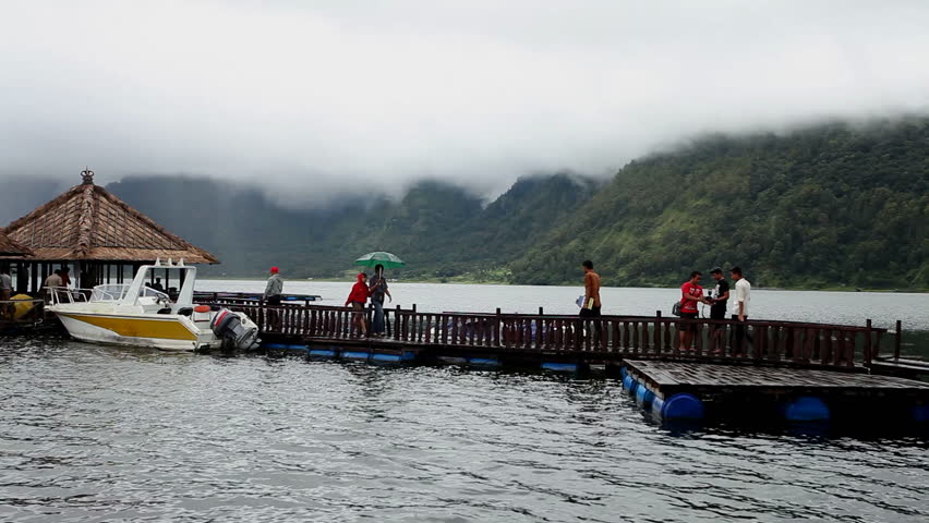 LAKE BATUR, BALI - JANUARY 21: Tourist crossing jetty to restaurant on Lake Batur on January 21, 2012 in Bali, Indonesia. Inhabitants of the lake rely on tourism and fishing for their subsistence. 