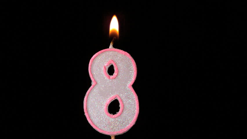 Eight birthday candle flickering and extinguishing on black background in slow motion