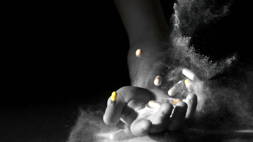 Hand holding pills and white powder dropping dead in slow motion