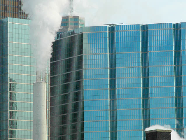 Time lapse. Smokestack puffs it out in the big city.