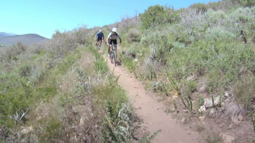 Mountain bikers pedal down dusty trail