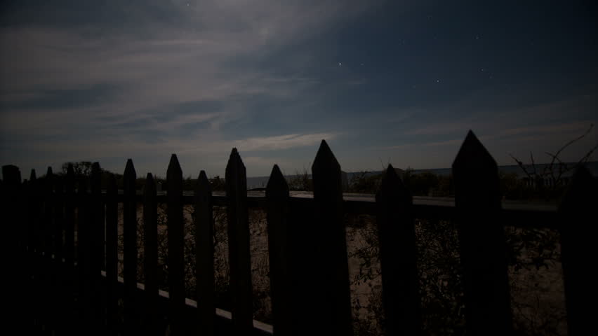 Graveyard night sky time-lapse moving along fence with tombstones
