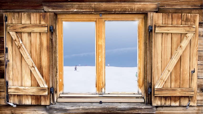 Mountain hut of the alps with skiing scene reflecting in the window