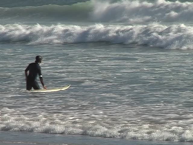 Young man running with his surfboard into the waves 