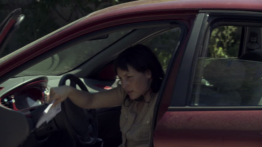 Two people get out of their cars after a collision, inspect the damage and exchange insurance details. Moving close up.
