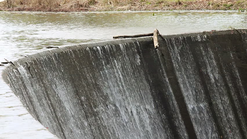 A dead tree limb dangles at the edge of a dam