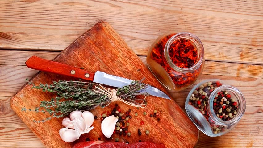 fresh raw beef meat fillet flesh with peppercorn and thyme ready to grill on wood figured old style board over table with spices in glass