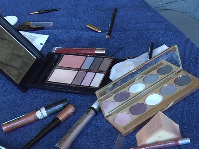 Open pieces of various make-up kits and cosmetics spread out on a blue towel