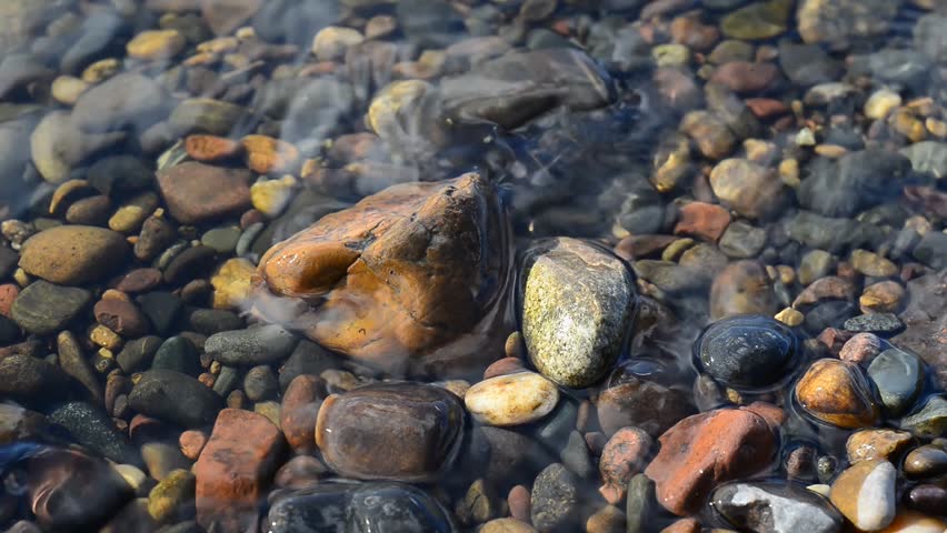 Sea cost water tides over pebble stones 