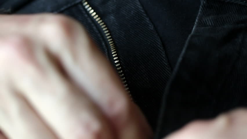 Zipping up the fly on a pair of blue denim jeans. Front view, shot with a macro lens and shallow depth of field.
