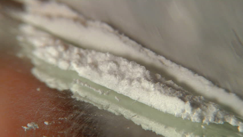 Cutting and snorting cocaine -Extreme macro closeup of cocaine being cut and snorted through a rolled up $100 bill