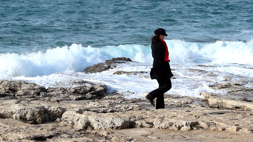Wavy walk - Woman with red scarf walking by the sea.