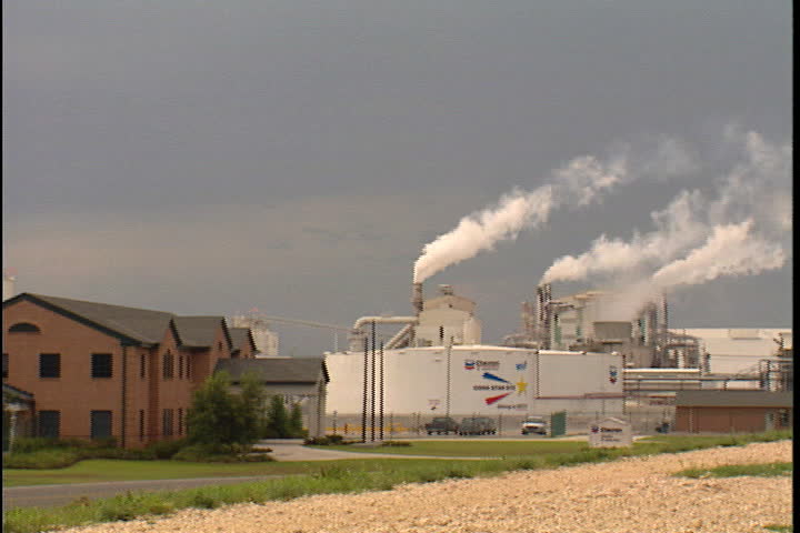 CONVENT, LOUISIANA - CIRCA SEPTEMBER 1999: Camera pans to Chevron oil storage tank and smokestacks spewing white smoke.