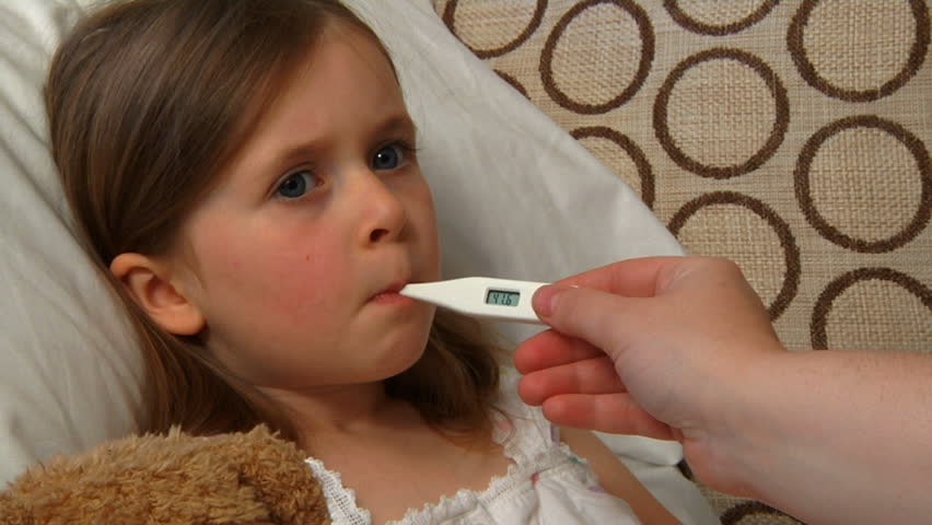 Child with a fever: sick little girl having her temperature taken with a digital thermometer