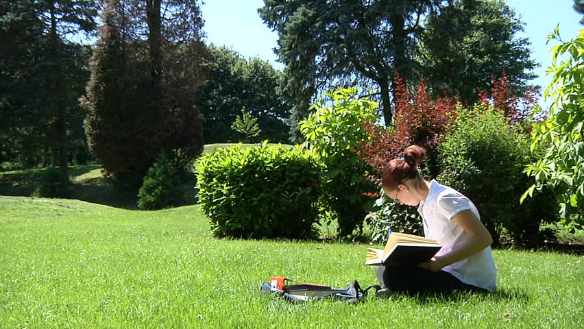 A student studying outdoors with textbook and folders