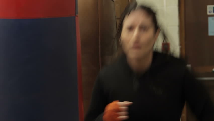 Female boxer - A female boxer is training with a punch bag, then turns to camera