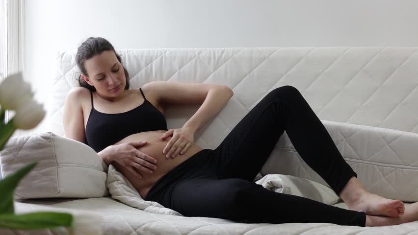 Young pregnant woman lying on sofa 