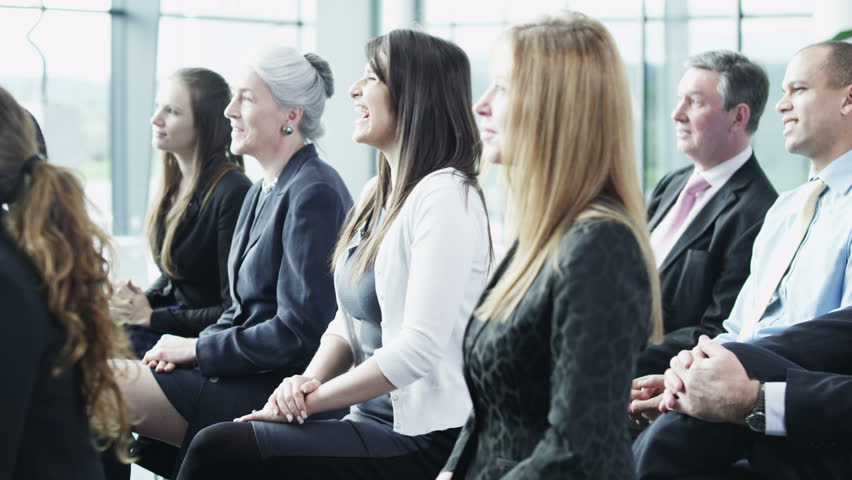 A multi ethnic group of business people of mixed ages are listening to a presentation at a business seminar. In slow motion. 