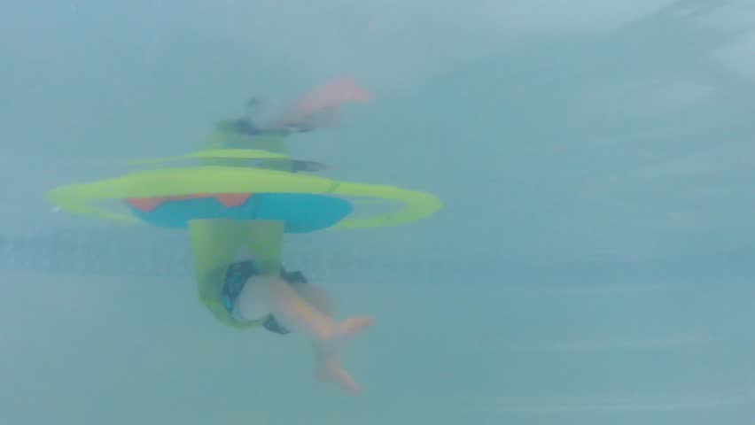 Underwater shot of a cute little baby boy at the swimming pool with his family.