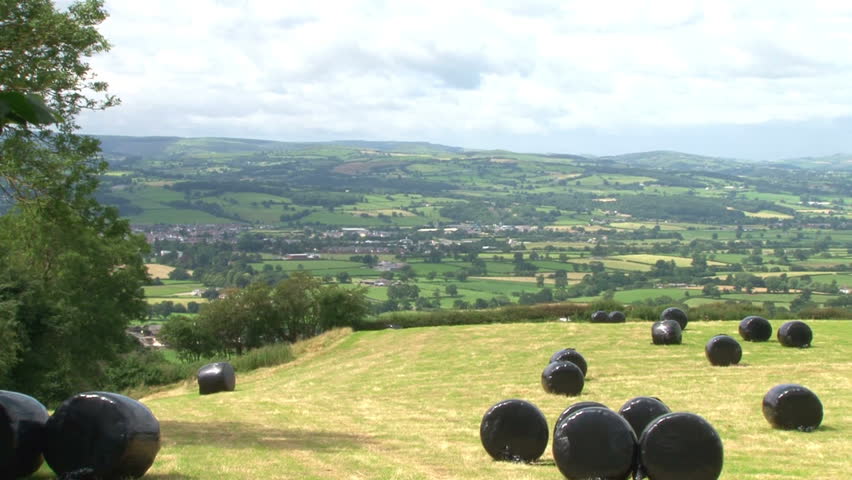 Hay bails in a field with a waterproof plastic covering.