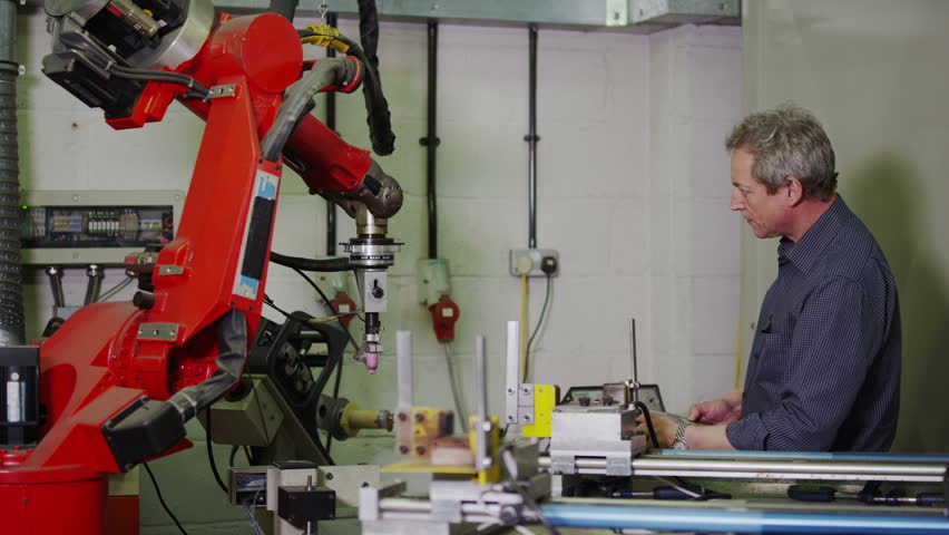 A mature male factory worker is concentrating as he operates one of the plant machines.