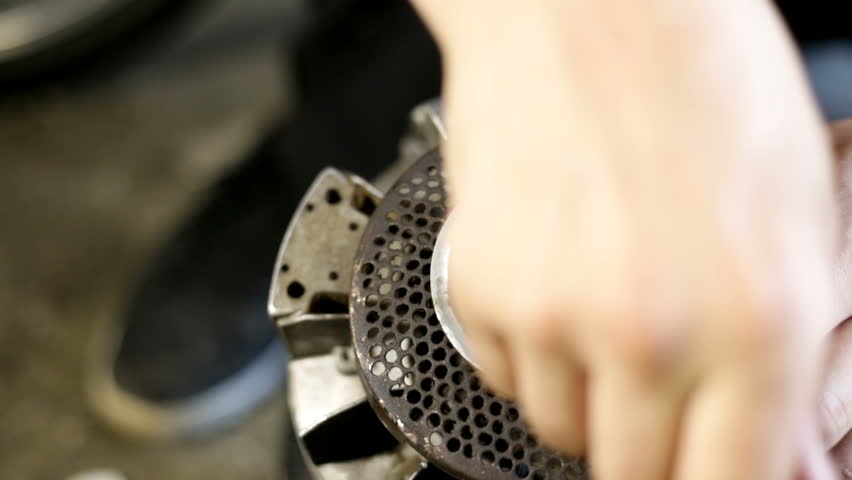 Young man cleaning a dirty engine of a mini motor. A lot of oil. Working in workshop on the floor. Unscrewing parts of the motor.