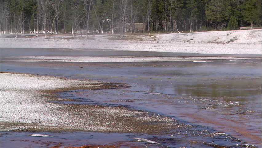 Zoom out from a large steaming geyser lake