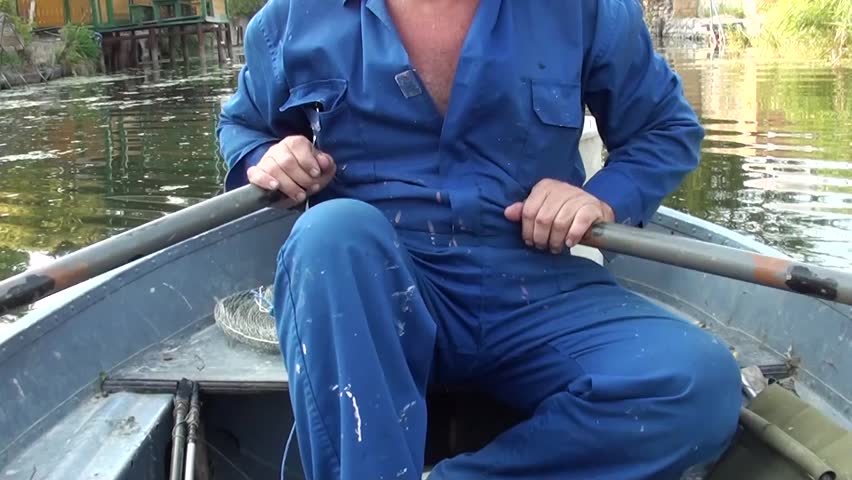 Man in overalls sculling a boat