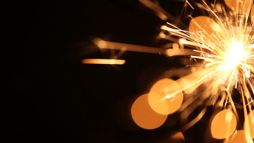 Video of sparkler and Christmas lights on black background with copy space.