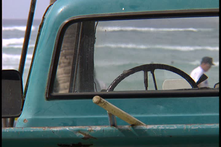 WAIKIKI BEACH, HONOLULU, HAWAII - JANUARY 30, 1997: scenic shots at Waikiki Beach, Hawaii: view of water framed by window of green truck parked on beach. 